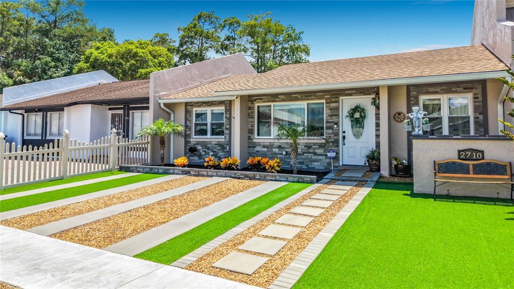 A single-story house with a stone facade, artificial turf lawn, and a paved driveway — 2710 CHARING CROSS WAY, ORLANDO, FL