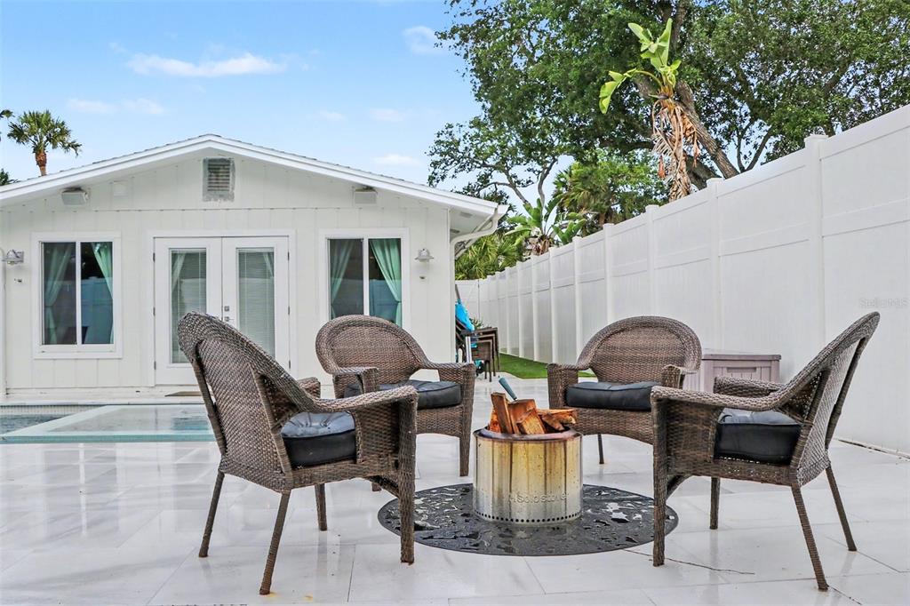 A patio features four wicker chairs arranged around a metal fire pit on white tiles — 5143 SANDY BEACH AVENUE, SARASOTA, FL