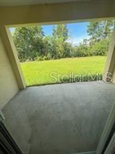 A concrete patio overlooks a grassy backyard with trees under a blue sky — 6 WOOD AMBER LANE UNIT B, PALM COAST, FL