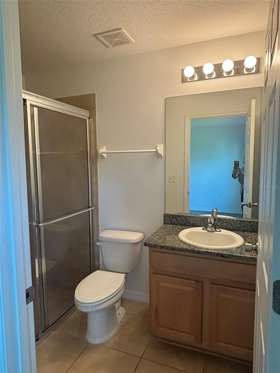 A bathroom features a glass-enclosed shower, a white toilet, and a vanity with a stone countertop — 6 WOOD AMBER LANE UNIT B, PALM COAST, FL