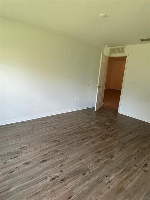 An empty room with light-colored walls and wood-look laminate flooring features an open doorway — 6 WOOD AMBER LANE UNIT B, PALM COAST, FL