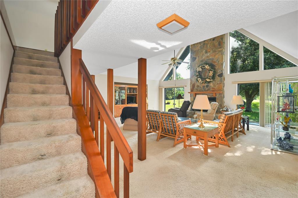 A living room features a stone fireplace, vaulted ceilings, carpeted stairs, and large windows — 821 N GOLF COURSE DRIVE, CRYSTAL RIVER, FL