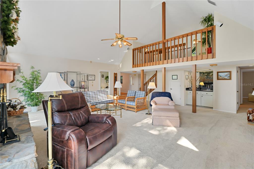 A spacious living room features a vaulted ceiling, a loft area, and a stone fireplace — 821 N GOLF COURSE DRIVE, CRYSTAL RIVER, FL