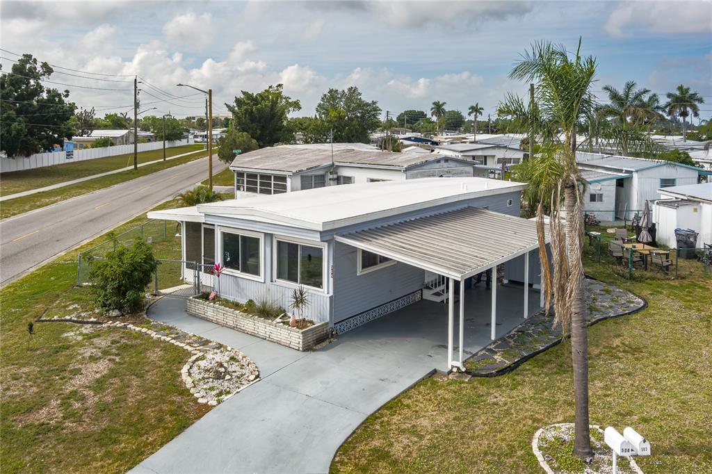 An elevated view of a light blue mobile home with a carport and palm tree — 504 50TH AVENUE DR W, BRADENTON, FL