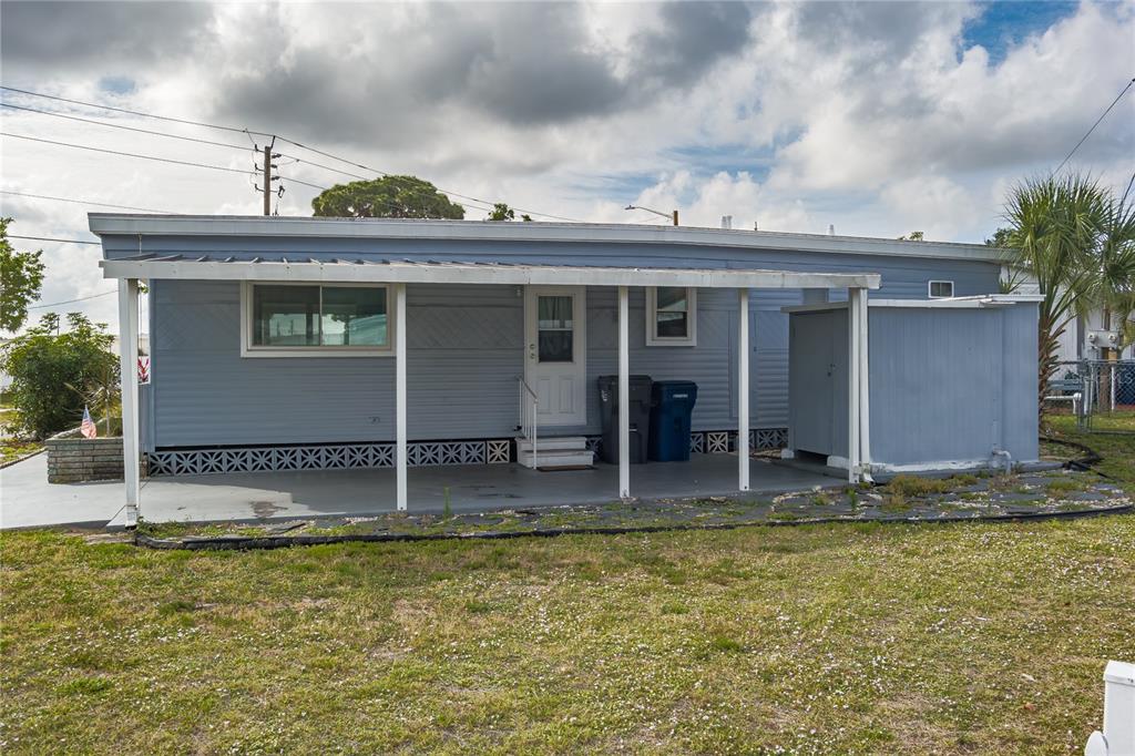 A light blue mobile home features a covered patio, white support posts, and lattice skirting — 504 50TH AVENUE DR W, BRADENTON, FL