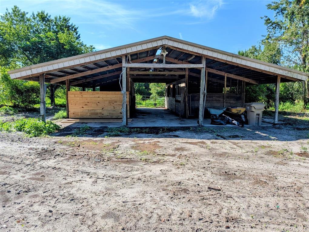 A wooden horse barn with a metal roof stands on a dirt lot — 21320 SENECA HILLS ROAD, EUSTIS, FL