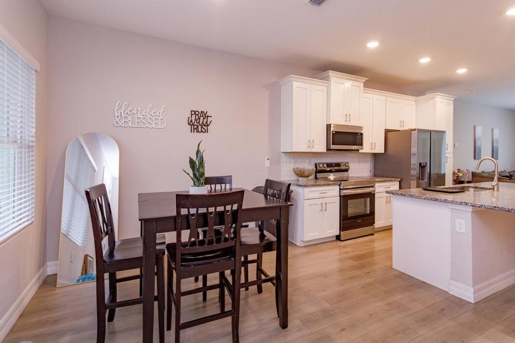 A dining area with a wooden table and chairs sits adjacent to a modern kitchen — 884 KLONDIKE STREET, WINTER GARDEN, FL