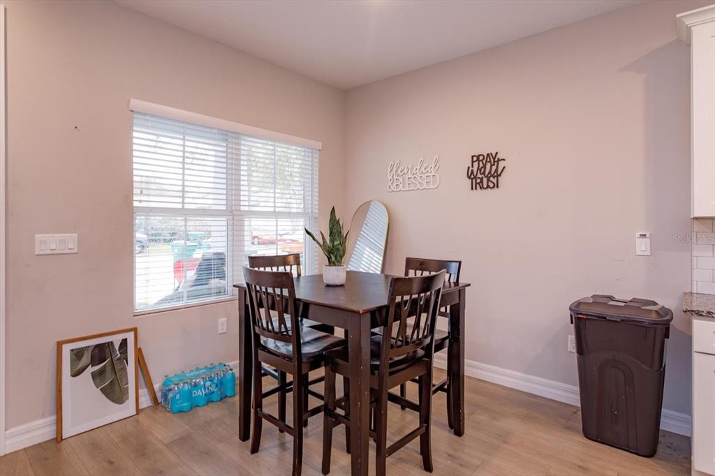 A dining area features a dark wood table with four chairs, a window, and wall decor — 884 KLONDIKE STREET, WINTER GARDEN, FL