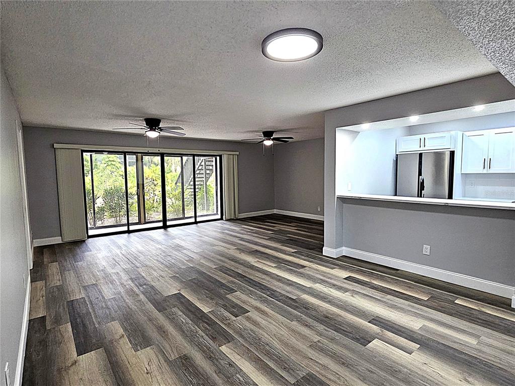 An open-concept living area features wood-look flooring, two ceiling fans, and a kitchen pass-through window — 1720 GLENHOUSE DRIVE UNIT 328, SARASOTA, FL