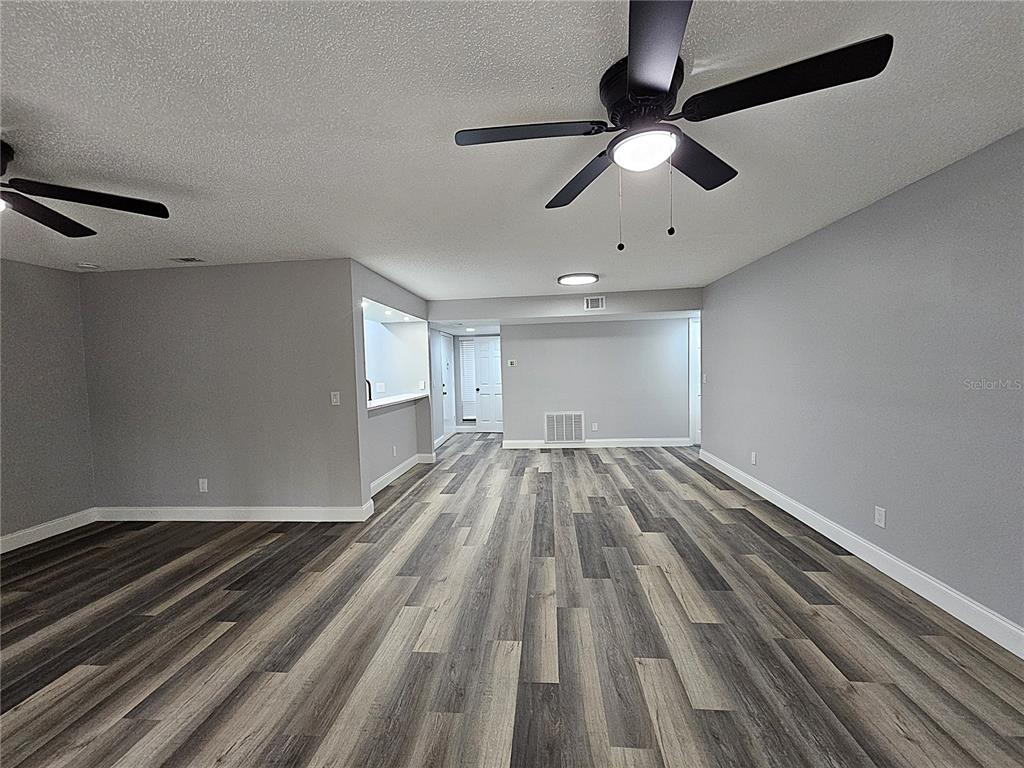 An empty room features gray walls, wood-look flooring, and two ceiling fans — 1720 GLENHOUSE DRIVE UNIT 328, SARASOTA, FL