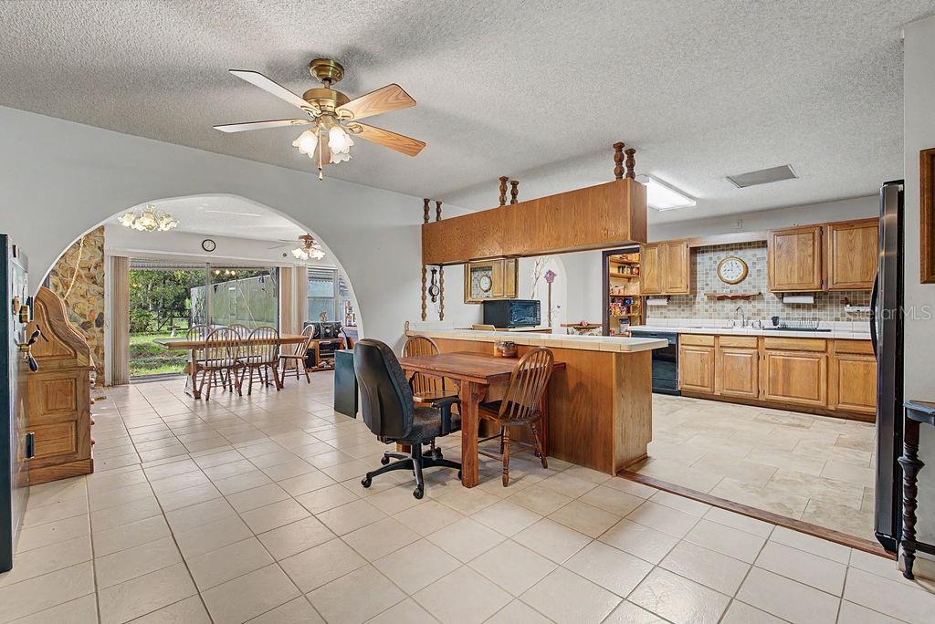 A kitchen with wood cabinets and a breakfast bar opens into a dining area — 12960 SE 114TH PLACE, DUNNELLON, FL