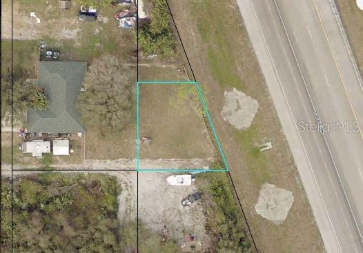 An aerial view shows a vacant, rectangular plot of land outlined in blue near a road — I-95, VERO BEACH, FL