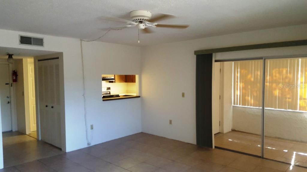 An interior view of a living room with tile flooring, a ceiling fan, and a pass-through — 4600 98TH WAY N UNIT 306, ST PETERSBURG, FL