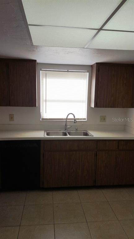 A kitchen features wood-grain cabinets, a double-basin sink, and a window with blinds — 4600 98TH WAY N UNIT 306, ST PETERSBURG, FL