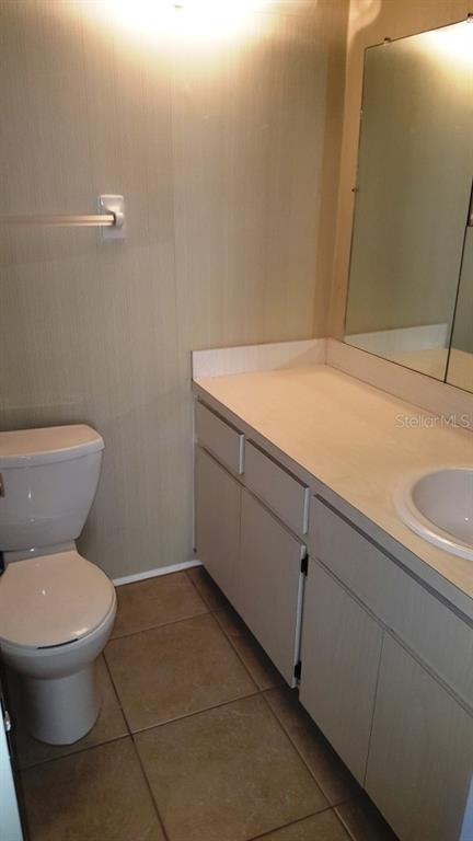 A bathroom featuring a white toilet, a vanity with a sink, and a wall mirror — 4600 98TH WAY N UNIT 306, ST PETERSBURG, FL