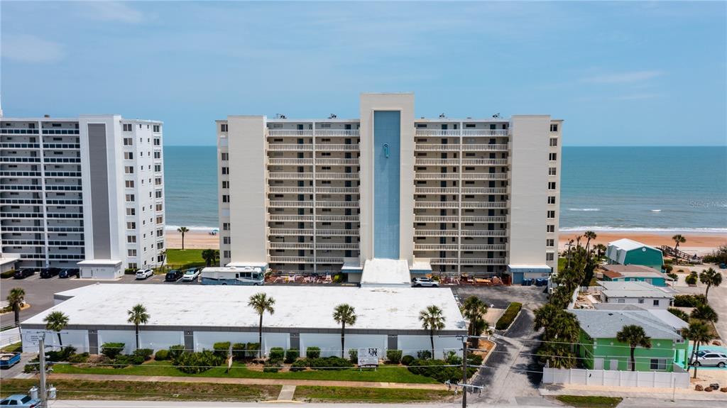 An exterior view of a multi-story beachfront condominium building with a flat-roofed parking structure — 1133 OCEAN SHORE BOULEVARD UNIT 302, ORMOND BEACH, FL
