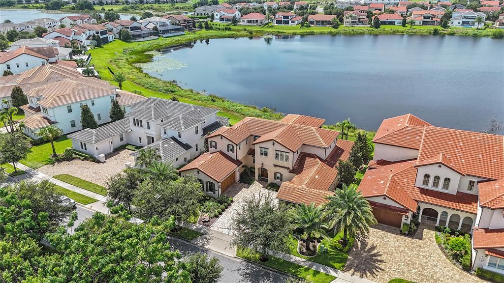 An aerial view shows several large houses with terracotta roofs situated along a lake — 15475 SHOREBIRD LANE, WINTER GARDEN, FL