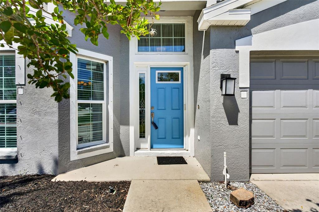 The exterior of a house features a blue front door, gray siding, and a garage — 4623 SANIBEL WAY, BRADENTON, FL