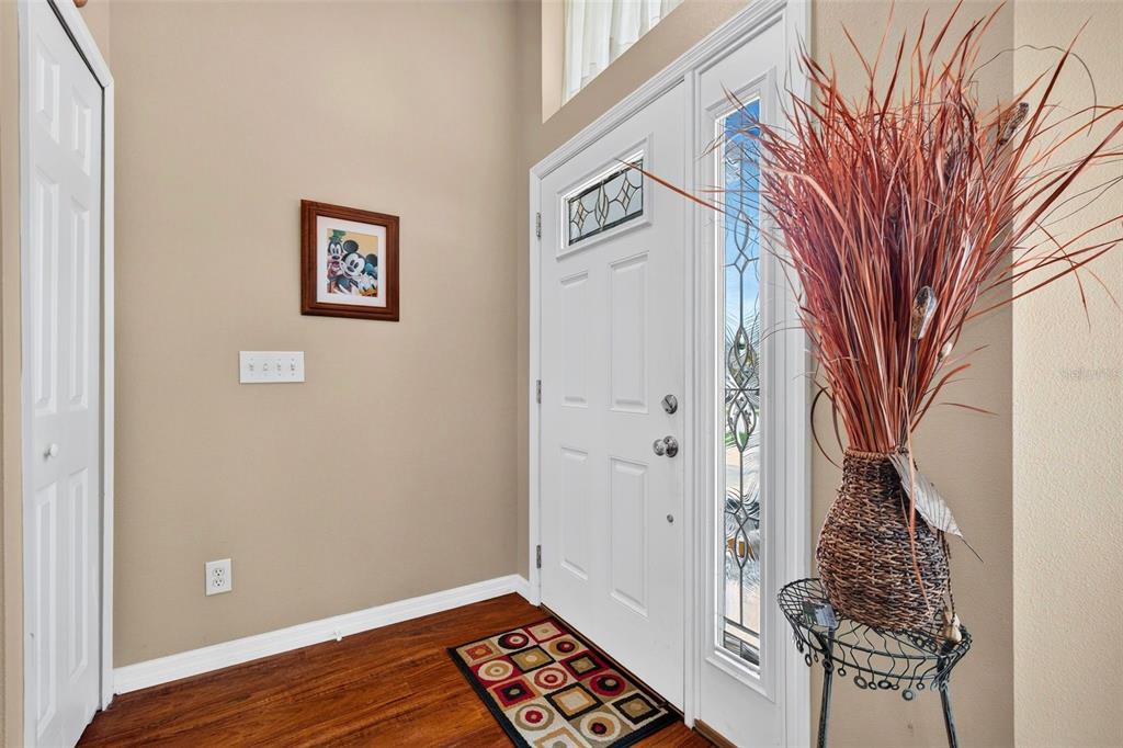 An entryway features a white front door with a sidelight, wood flooring, and a patterned rug — 4623 SANIBEL WAY, BRADENTON, FL
