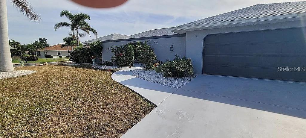 A single-story house features a gray garage, a curved walkway, and a landscaped front yard — 1840 FLAMETREE LANE, VENICE, FL