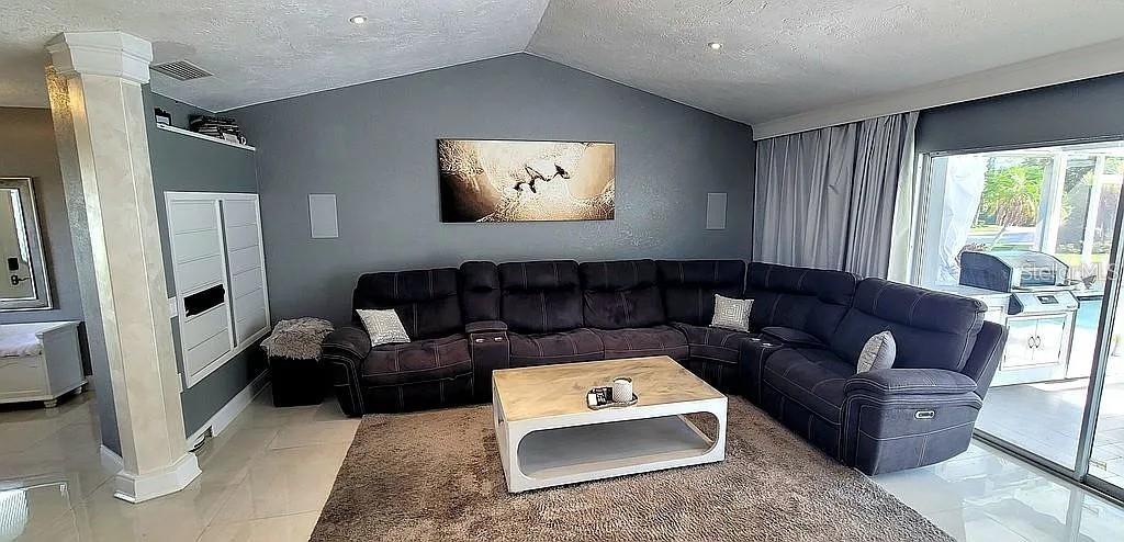 A living room features a large dark sectional sofa, a coffee table, and gray walls — 1840 FLAMETREE LANE, VENICE, FL