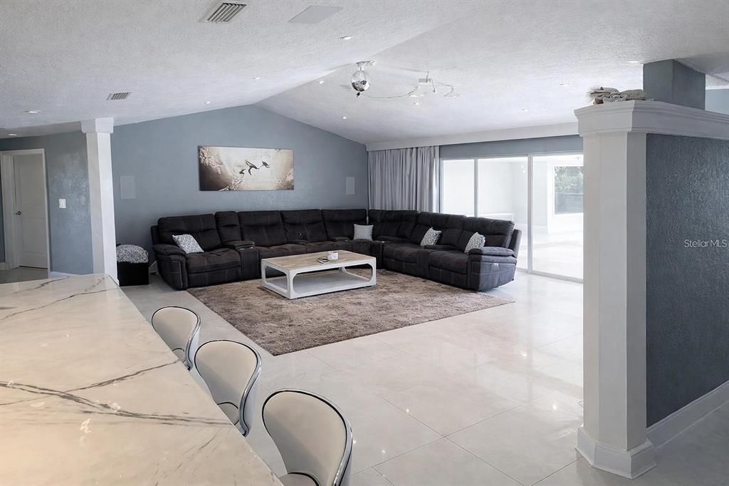 A spacious living room features a large sectional sofa, marble-topped island, and light-colored tile flooring — 1840 FLAMETREE LANE, VENICE, FL