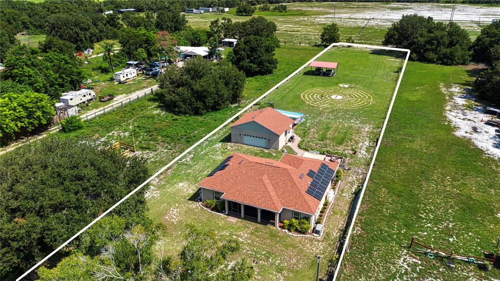 An aerial view shows a house with solar panels, a detached garage, and a lawn labyrinth — 13522 COUNTY ROAD 672 HIGHWAY, RIVERVIEW, FL