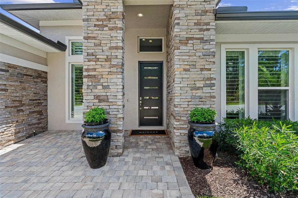 The front entrance features a dark door with glass inserts between two stone-clad pillars — 463 STIRLING BRIDGE DRIVE, ORMOND BEACH, FL