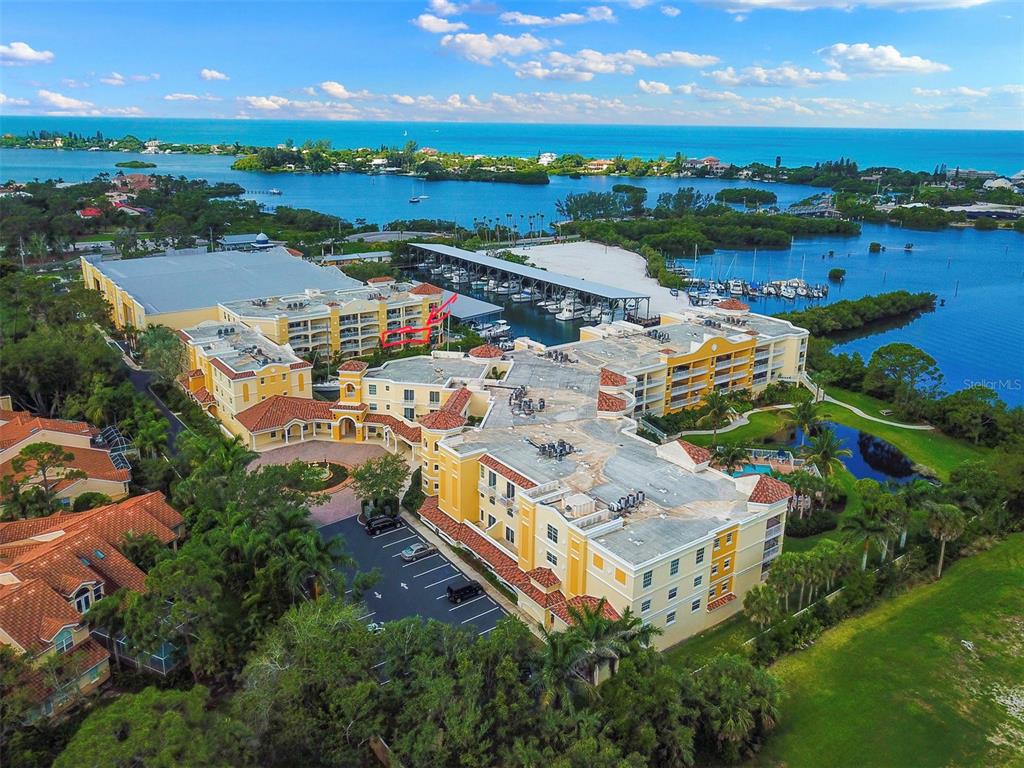 An aerial view shows a large multi-story apartment complex with a marina and water views — 14041 BELLAGIO WAY UNIT 214, OSPREY, FL
