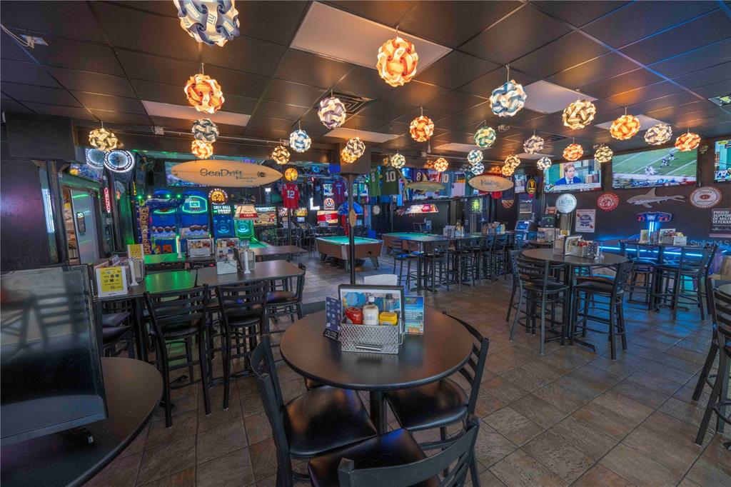 This interior view shows a sports bar with multiple tables, pool tables, and hanging light fixtures — 1368 OCEAN SHORE BOULEVARD, ORMOND BEACH, FL