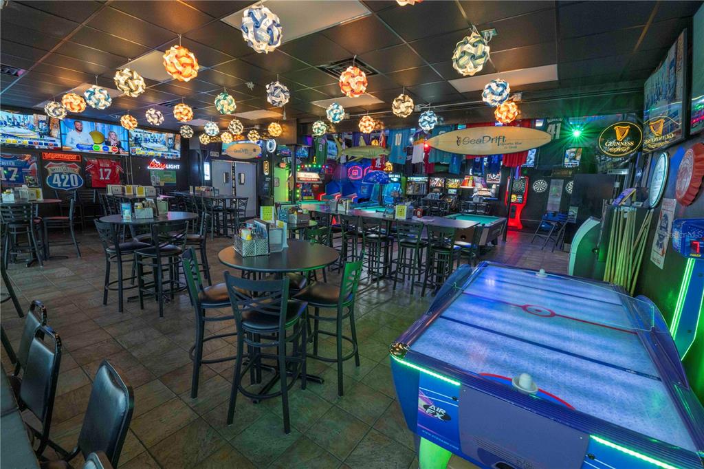 A sports bar features high-top tables, an air hockey table, and decorative hanging light fixtures — 1368 OCEAN SHORE BOULEVARD, ORMOND BEACH, FL