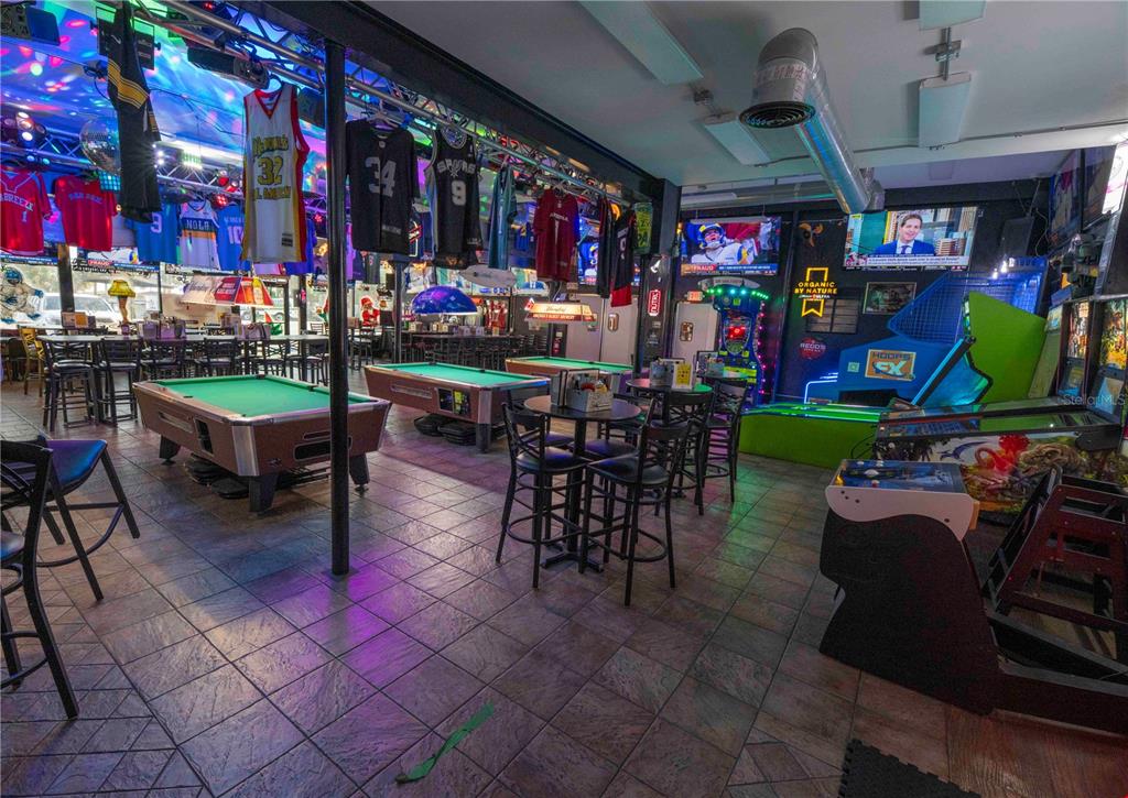 A sports bar interior features pool tables, high-top seating, arcade games, and jerseys hanging overhead — 1368 OCEAN SHORE BOULEVARD, ORMOND BEACH, FL