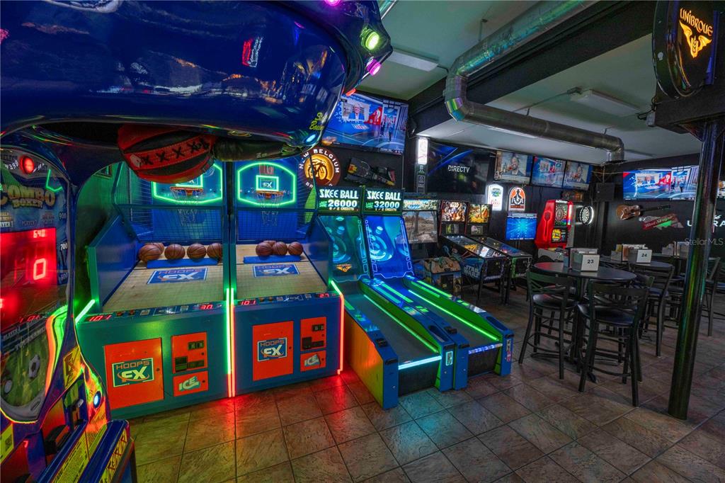 An indoor arcade area features multiple basketball and skee-ball machines near a seating area — 1368 OCEAN SHORE BOULEVARD, ORMOND BEACH, FL