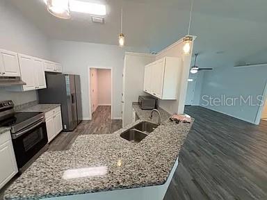 A kitchen features white cabinets, granite countertops, stainless steel appliances, and wood-look flooring — 15023 SE 93RD COURT, SUMMERFIELD, FL