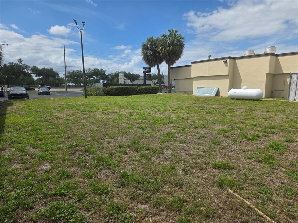 An empty grassy lot sits beside a commercial building with a large propane tank — 5101 E COLONIAL DRIVE, ORLANDO, FL