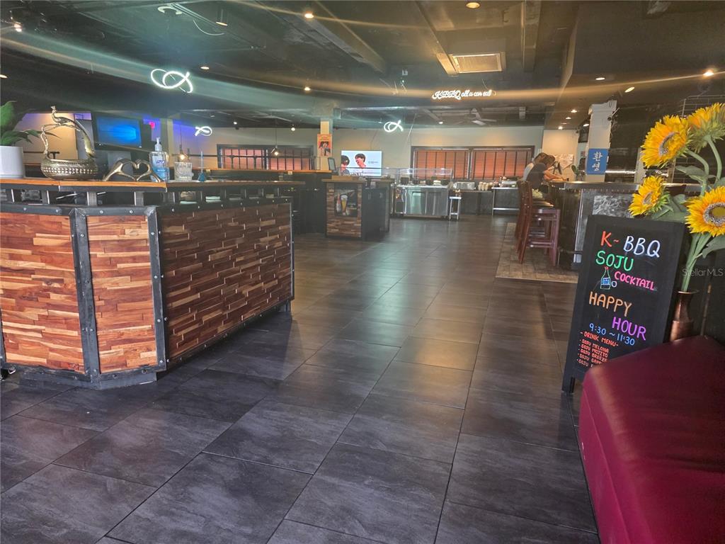 A restaurant interior features a wood-paneled bar, dark tile flooring, and a chalkboard menu sign — 5101 E COLONIAL DRIVE, ORLANDO, FL