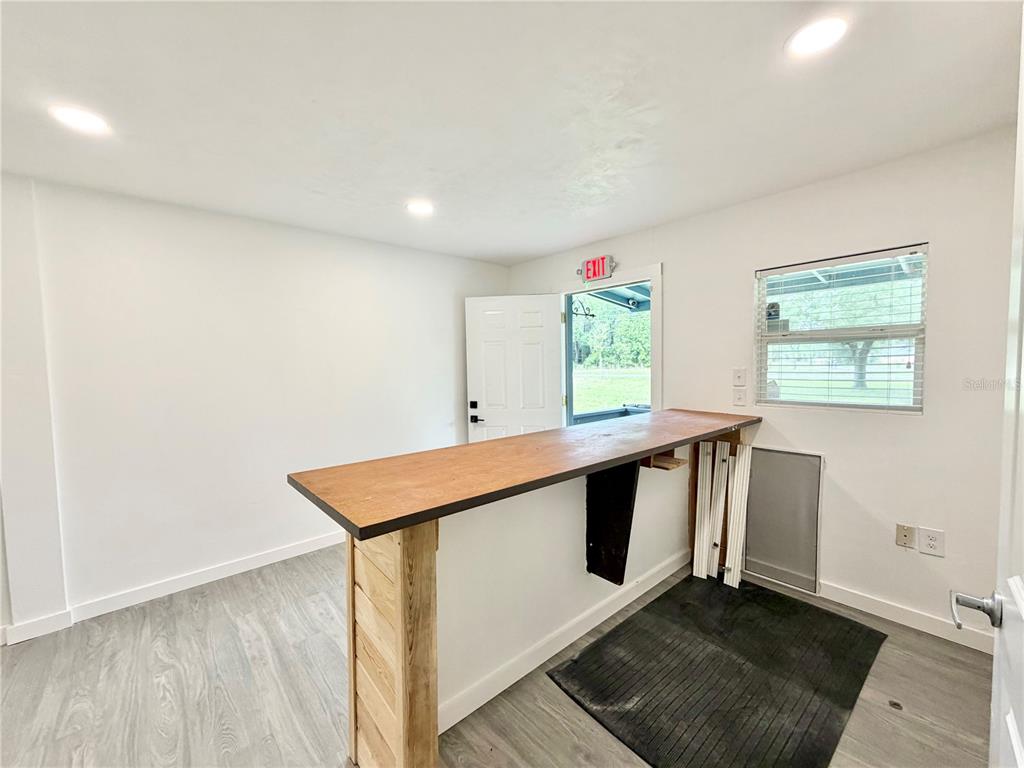 A room features a wooden bar counter, light-colored flooring, white walls, and an exit door — 683 N COURT STREET, BRONSON, FL