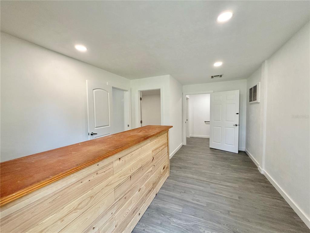 A room with gray wood-look flooring, white walls, recessed lighting, and a wooden bar counter — 683 N COURT STREET, BRONSON, FL