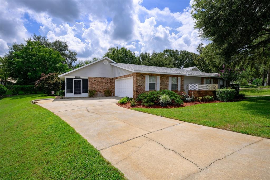 A single-story brick and siding house with a concrete driveway and a screened front porch — 2525 S GLEN EAGLES DRIVE, DELAND, FL