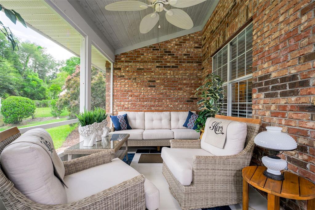 A covered patio features wicker furniture, a brick wall, and a ceiling fan — 2525 S GLEN EAGLES DRIVE, DELAND, FL