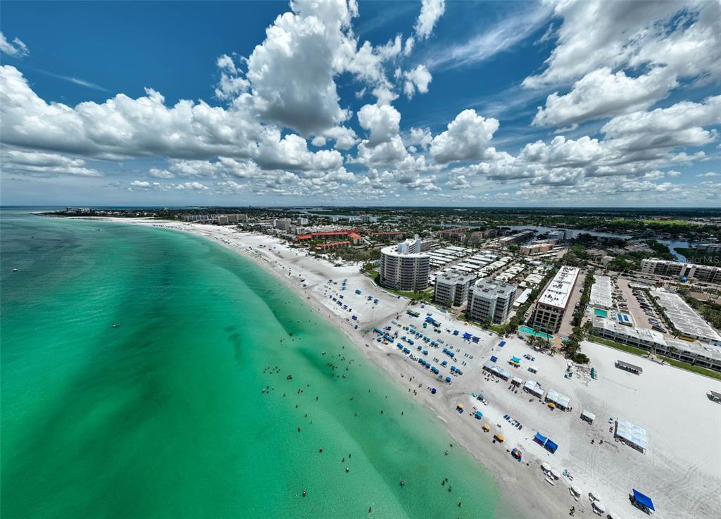 An aerial view of a white sand beach with turquoise water and nearby resort buildings — 6308 MIDNIGHT PASS ROAD UNIT 6, SARASOTA, FL
