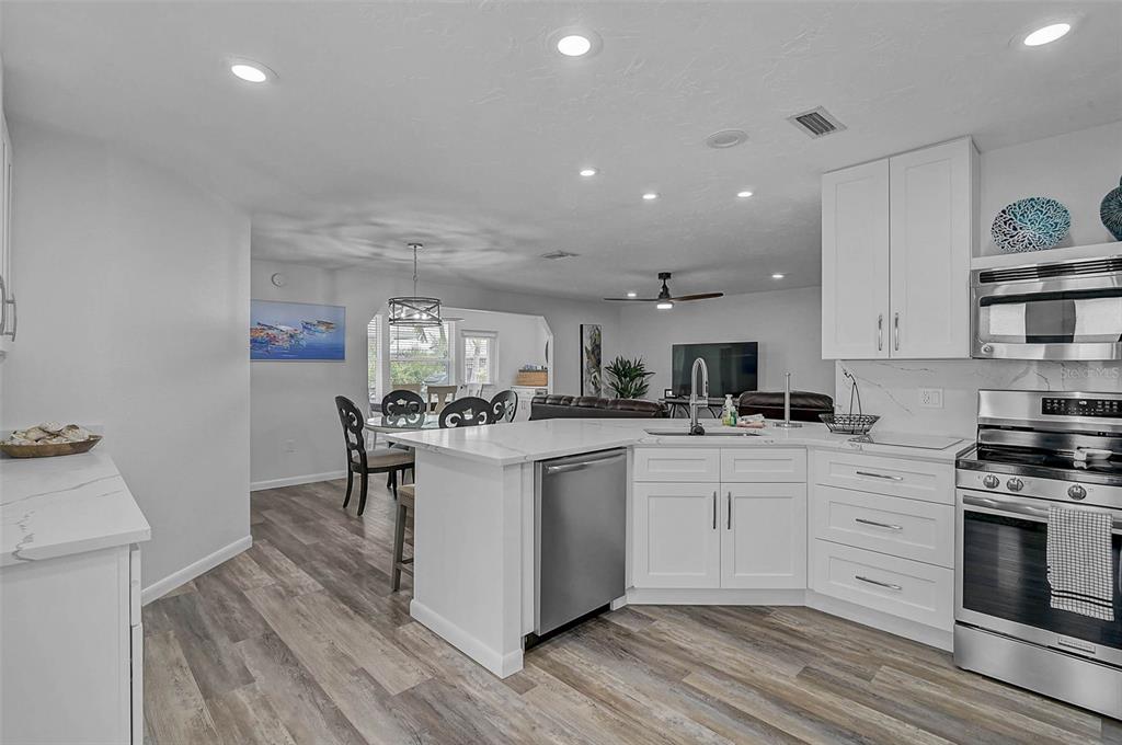 A modern kitchen features white cabinets, stainless steel appliances, and a peninsula island — 6308 MIDNIGHT PASS ROAD UNIT 6, SARASOTA, FL