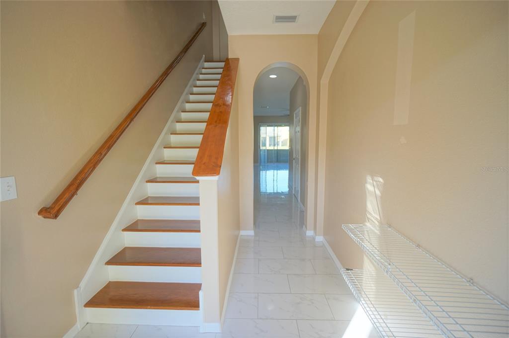 An entryway features a staircase with wooden treads, white tile flooring, and an arched hallway — 6888 46TH LANE N, PINELLAS PARK, FL