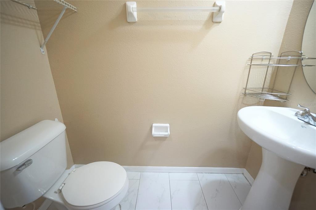 A small bathroom features a white pedestal sink, a toilet, and a wall-mounted towel bar — 6888 46TH LANE N, PINELLAS PARK, FL