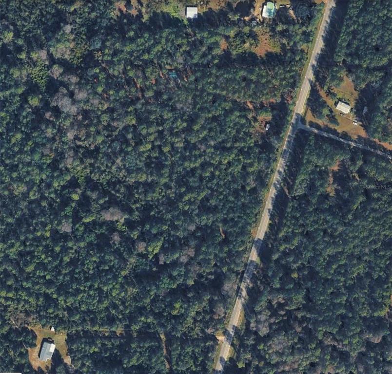 An aerial view shows a wooded lot bordering a paved road with scattered residential structures — 6366 COUNTY ROAD 315C, KEYSTONE HEIGHTS, FL