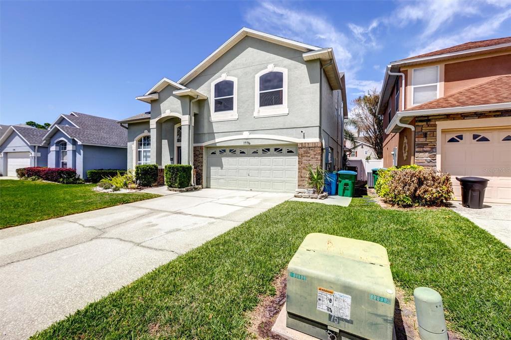 A two-story house with a light green stucco exterior, a two-car garage, and a driveway — 1776 BOBTAIL DRIVE, MAITLAND, FL