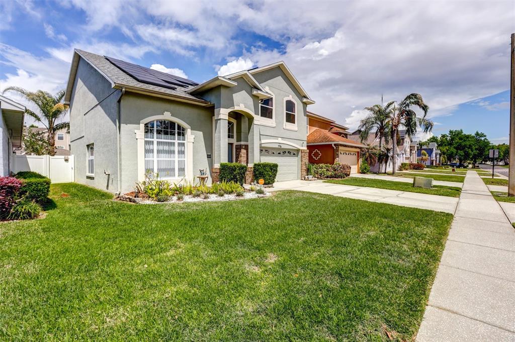A two-story suburban house with a light green exterior, solar panels, and a front lawn — 1776 BOBTAIL DRIVE, MAITLAND, FL