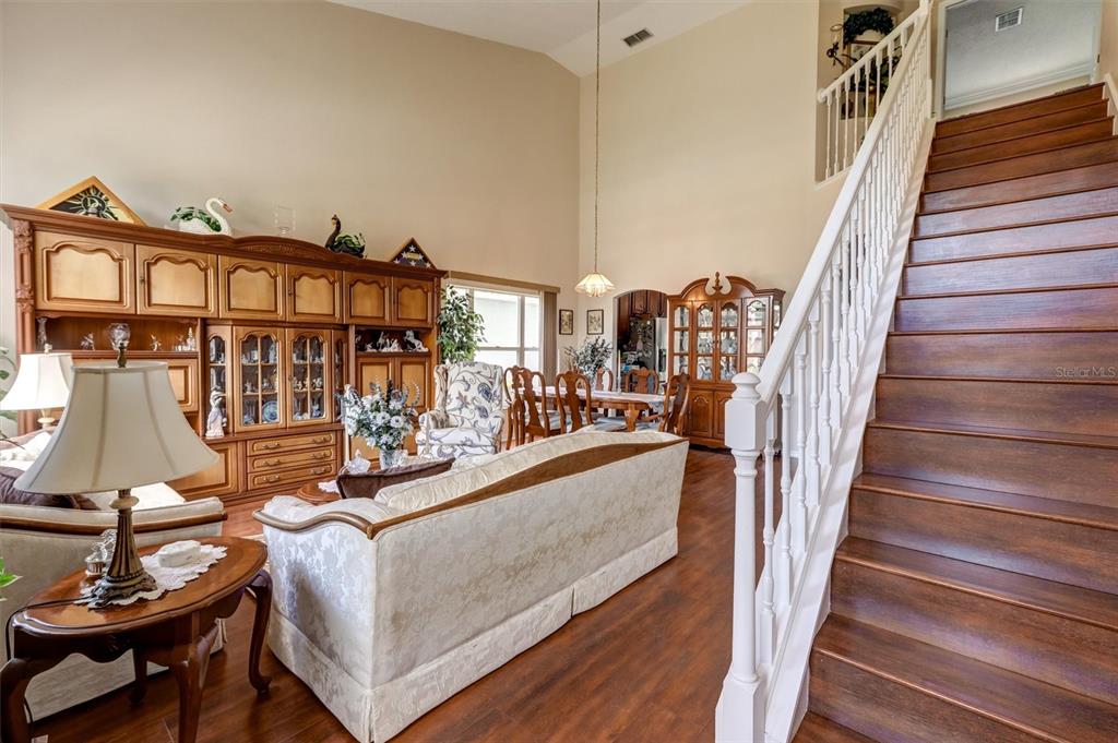 A living room with wood flooring, a staircase, and a large wooden wall unit — 1776 BOBTAIL DRIVE, MAITLAND, FL