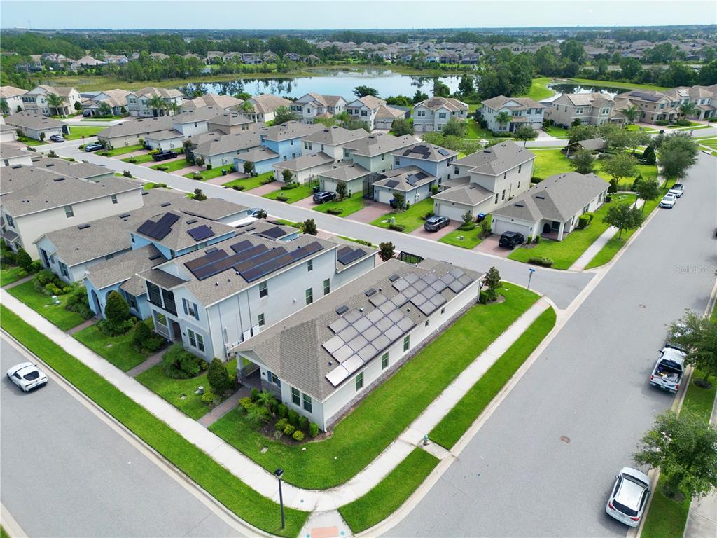 An aerial view shows suburban houses with solar panels on their roofs near a lake — 9357 JAYWOOD ROAD, WINTER GARDEN, FL