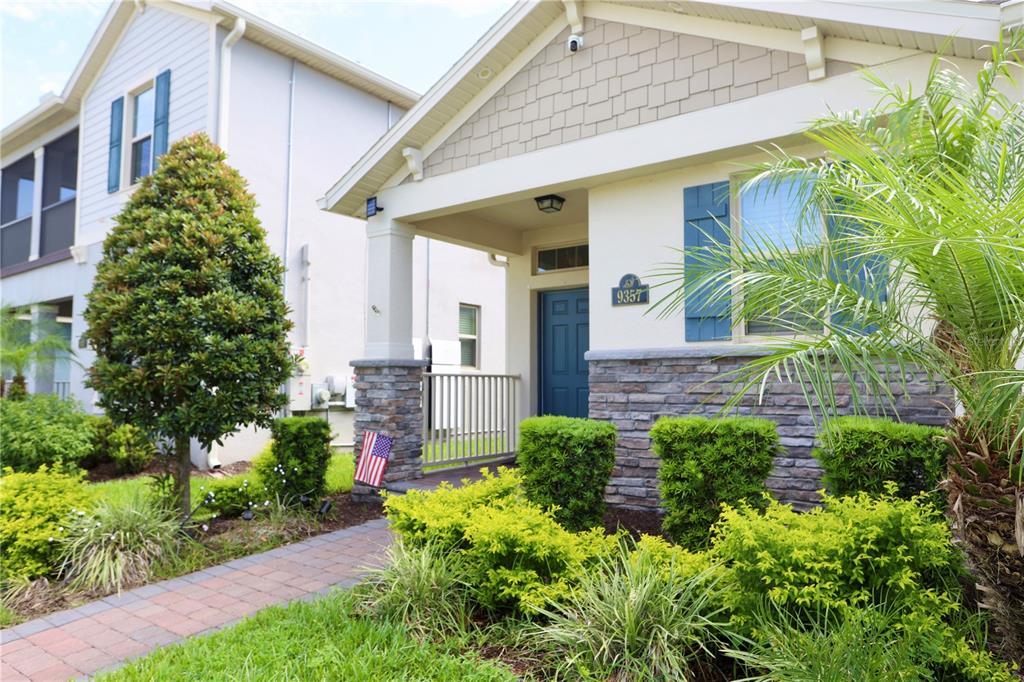 A single-story house exterior with a stone facade, blue front door, and a paved walkway — 9357 JAYWOOD ROAD, WINTER GARDEN, FL